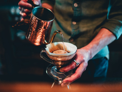 barista-pour-over-coffee-from-copper-kettle.webp